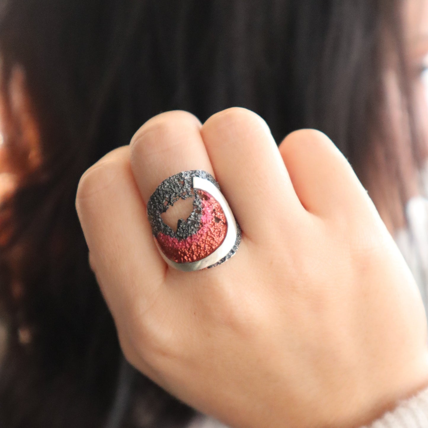 sterling silver wave ring with natural pink and orange pigment. shown on model.