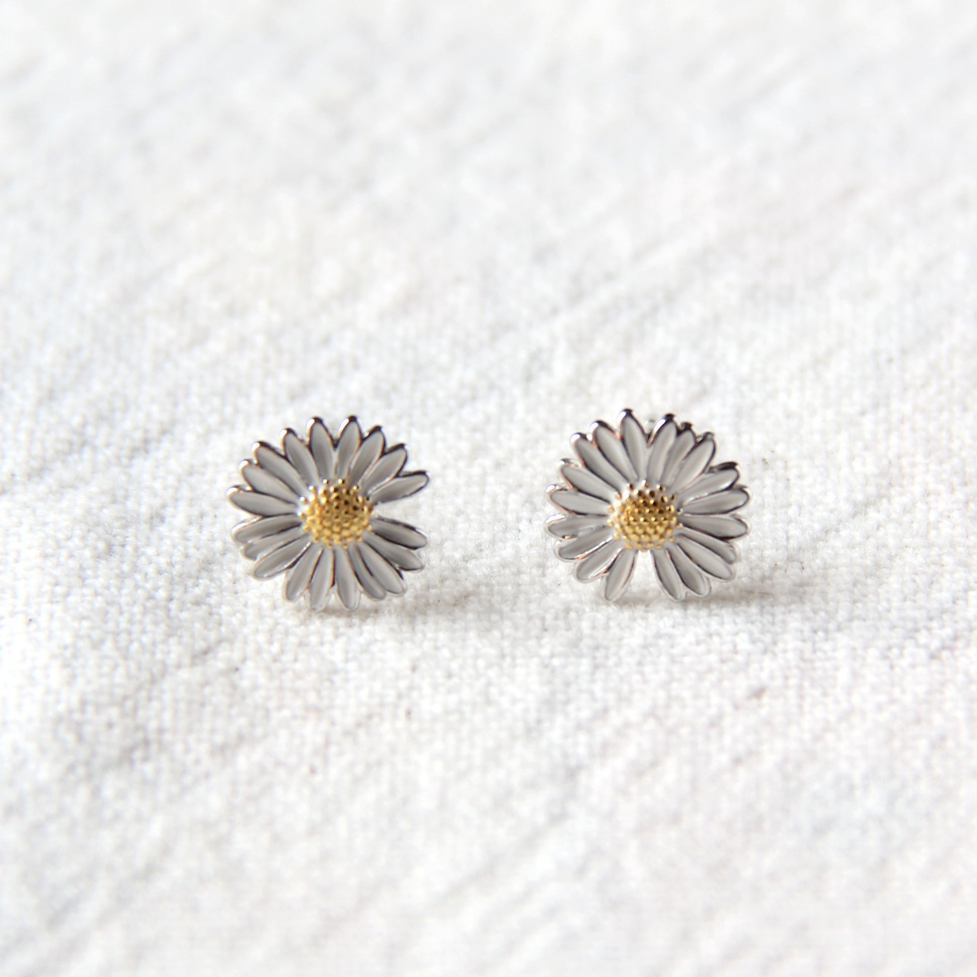 sterling silver daisy earrings with colored enamel. post closure.